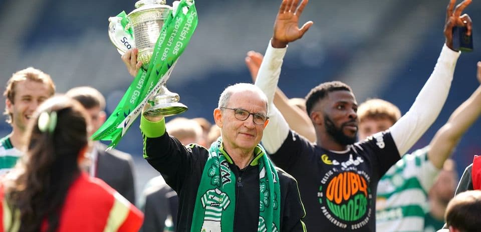 Man holding trophy with green ribbons, celebrating