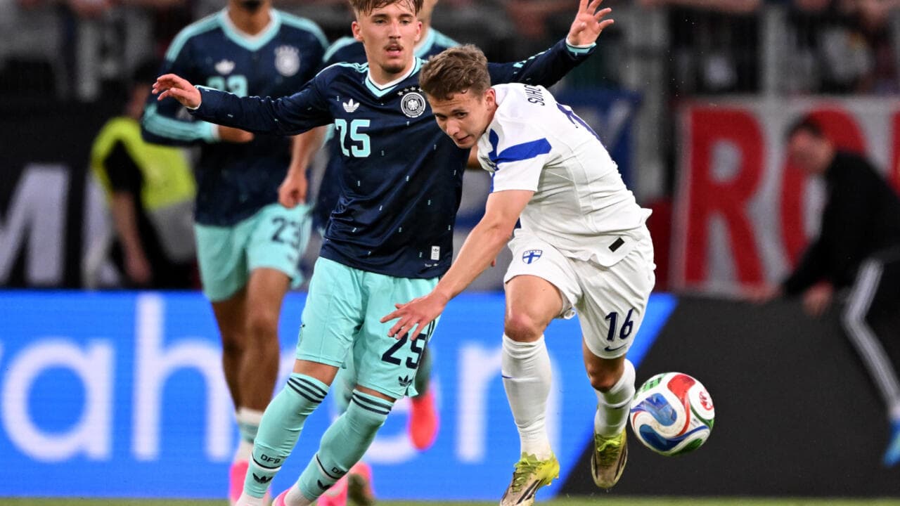 German player tackling Finnish player during match