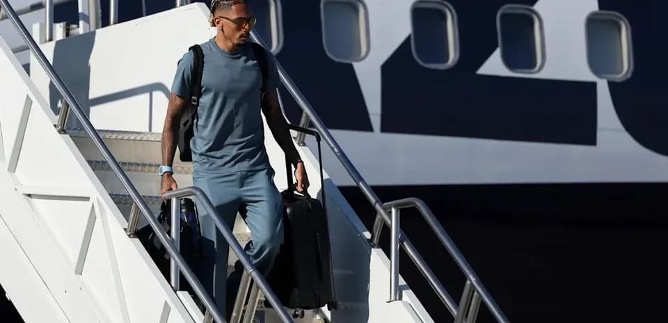 Player descending airplane steps with suitcase
