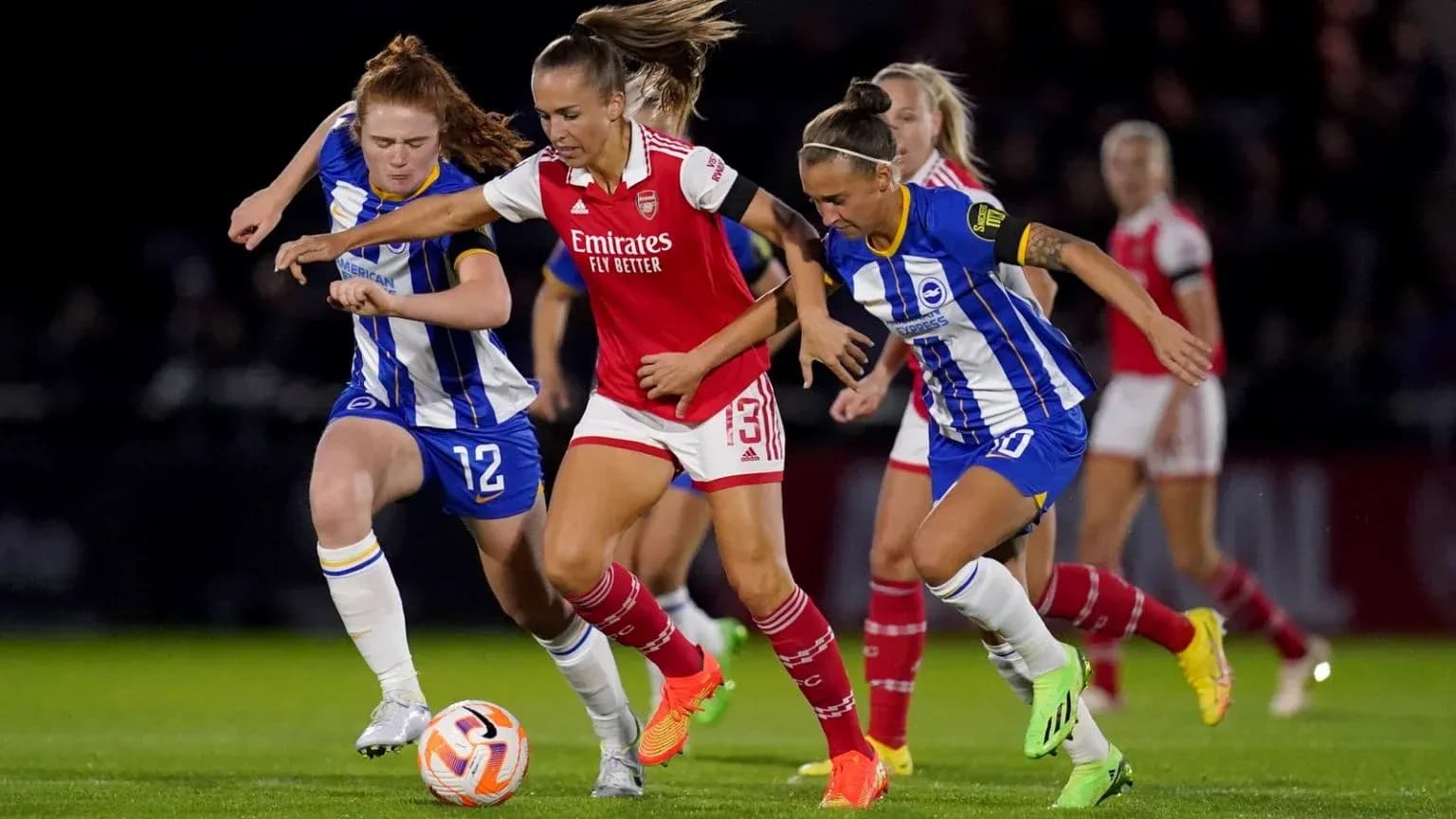 Brighton W players challenging Arsenal W for the ball