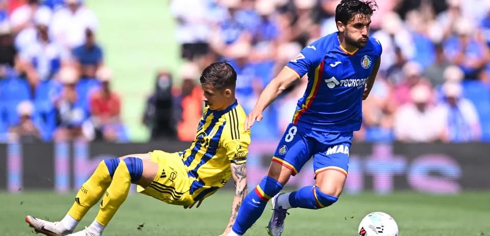 Getafe player evading Oviedo tackle during match