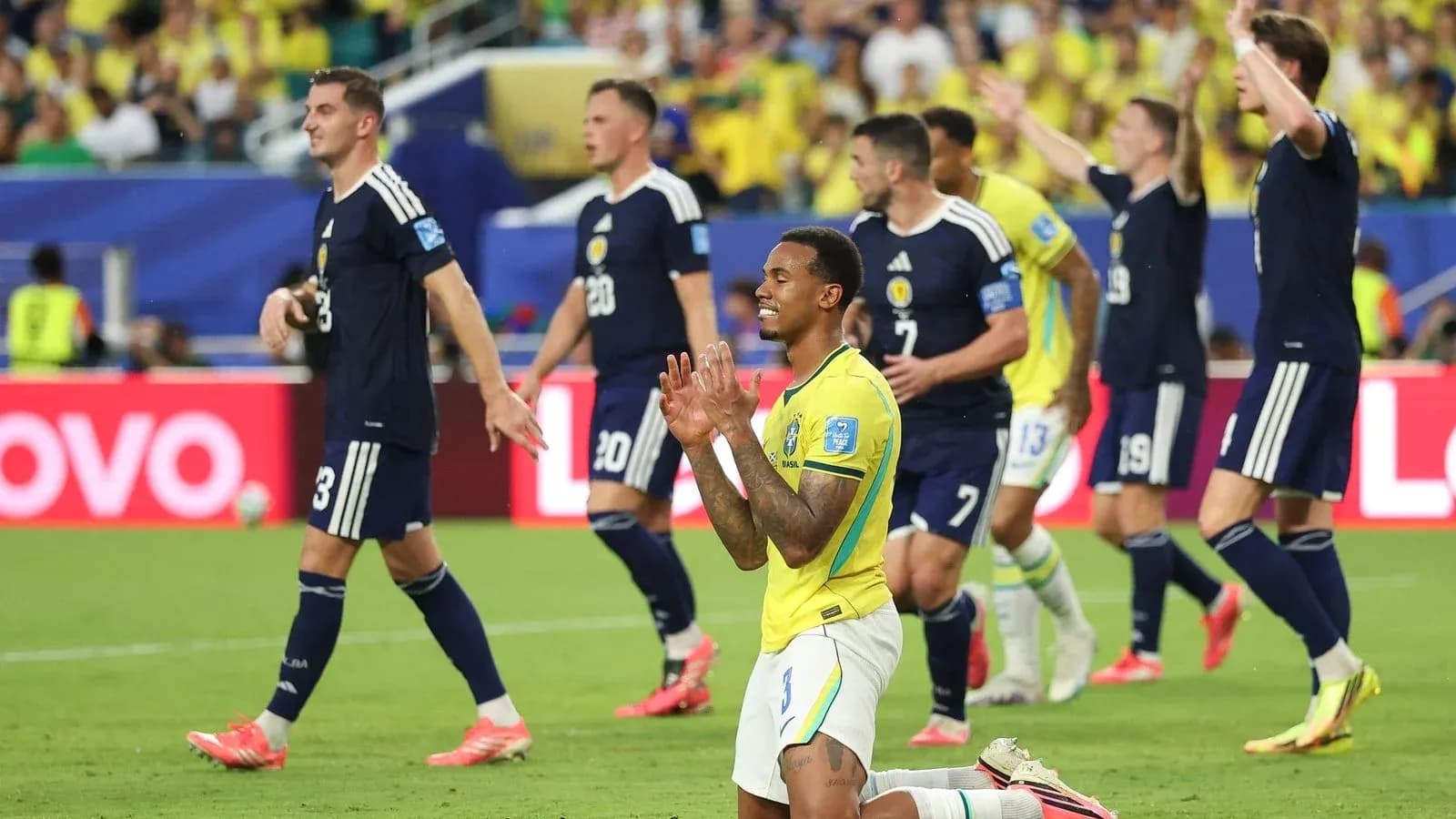 Brazilian player on knees as Scottish players celebrate