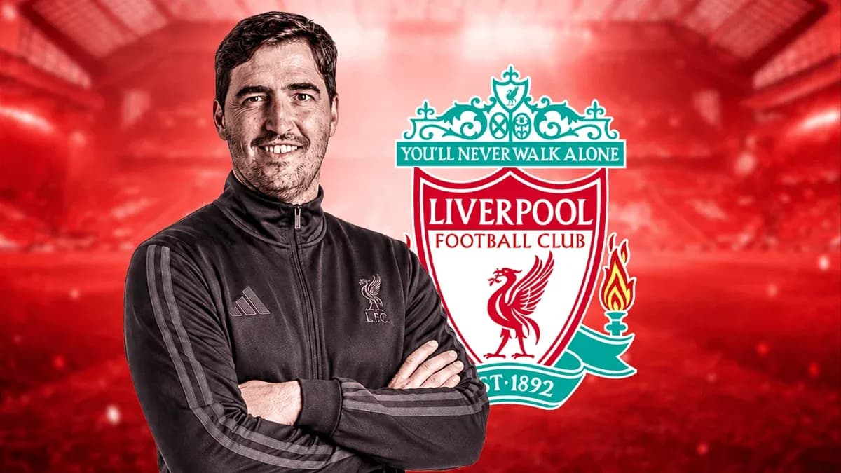 Coach posing with Liverpool FC logo in background