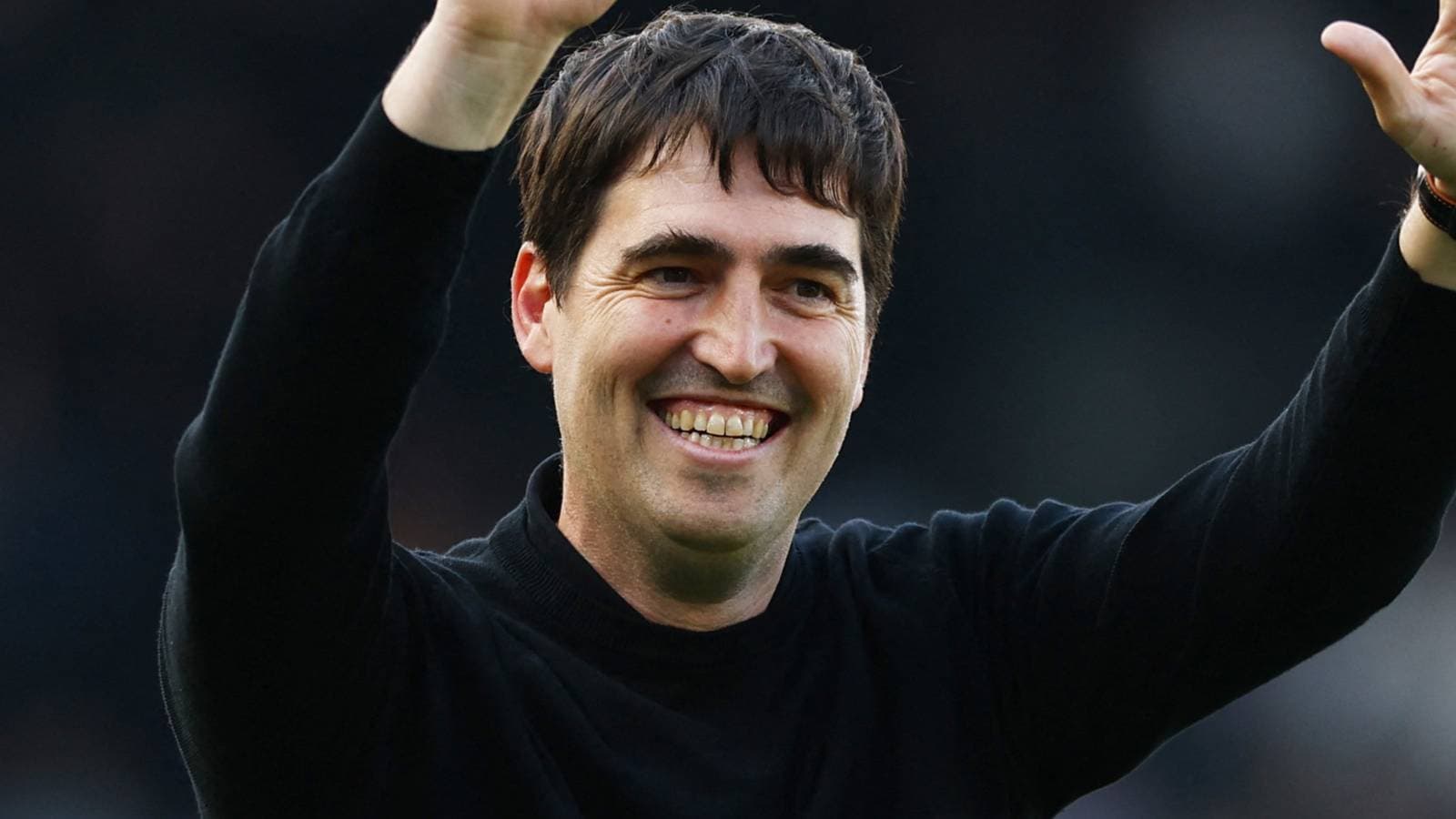 Man smiling and waving at the audience