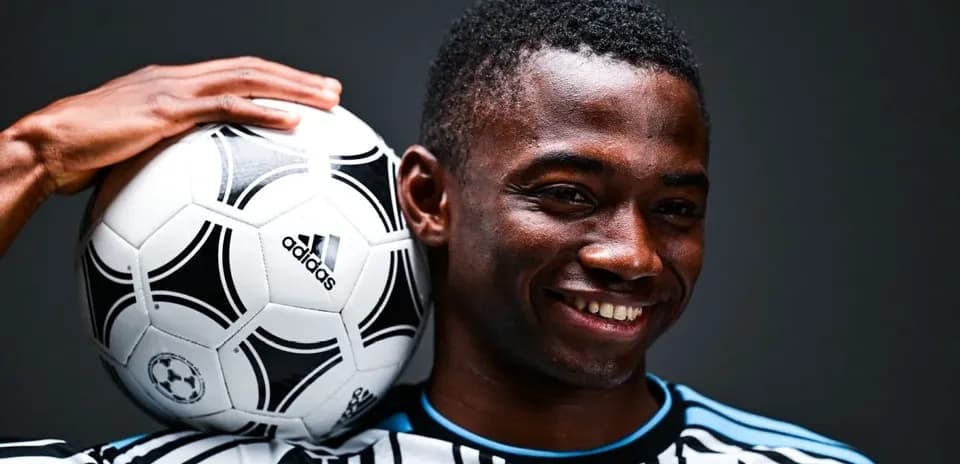 Player posing with a soccer ball on shoulder