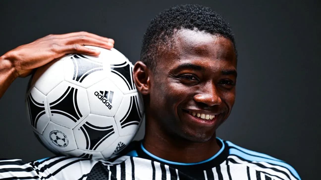 Player posing with a soccer ball on shoulder