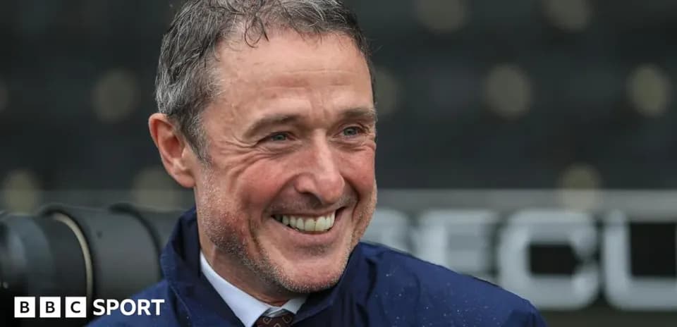Smiling man in a raincoat at a stadium
