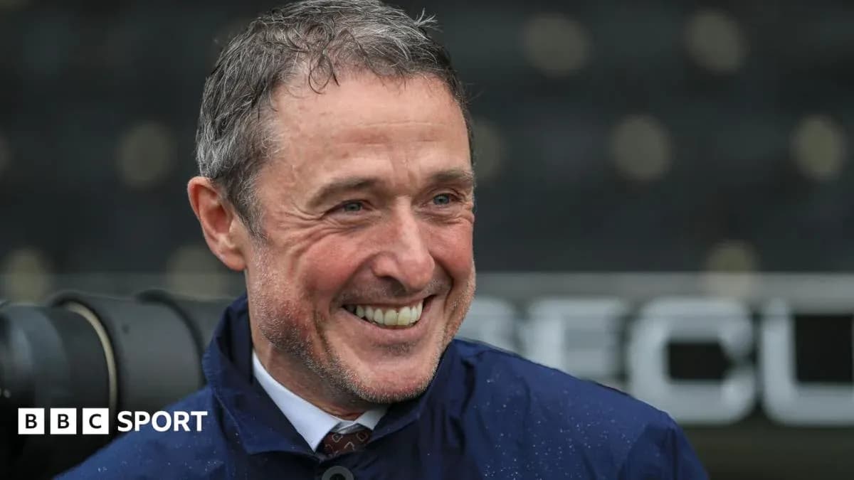 Smiling man in a raincoat at a stadium