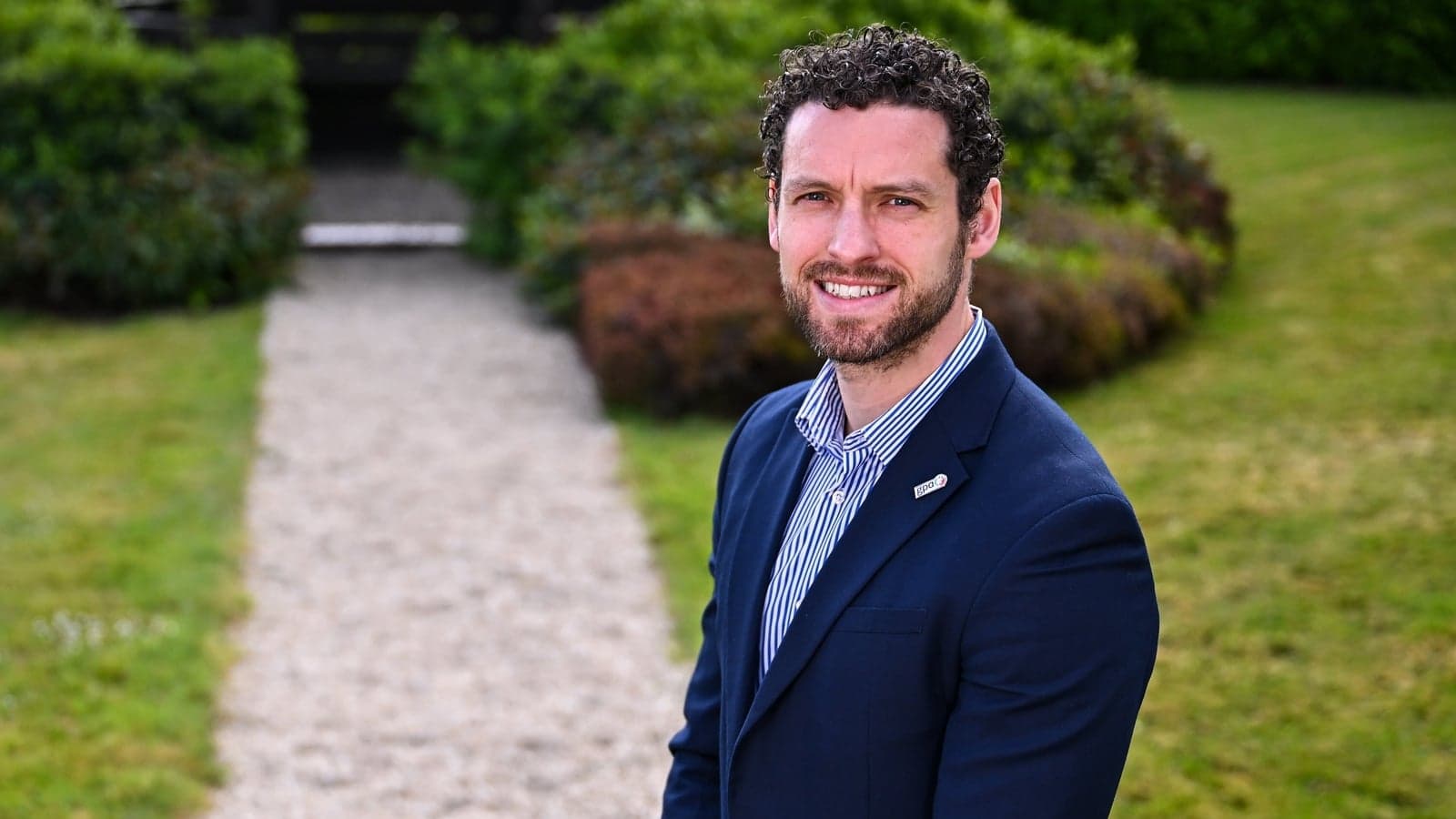 Man in a suit standing on a garden pathway