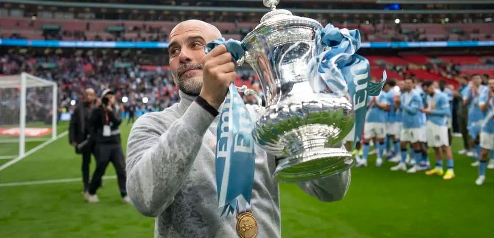 Manager holding trophy with team celebrating in background