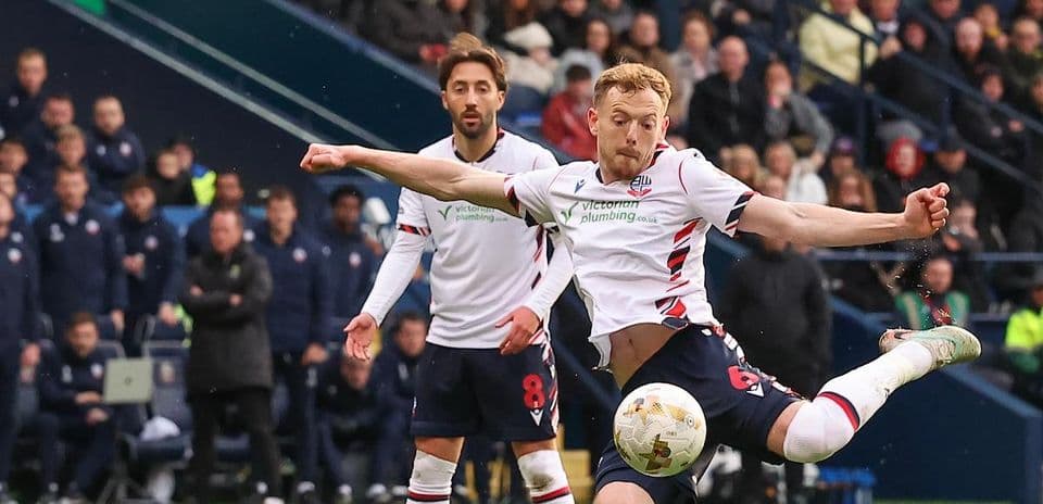 Bolton player striking ball during match action