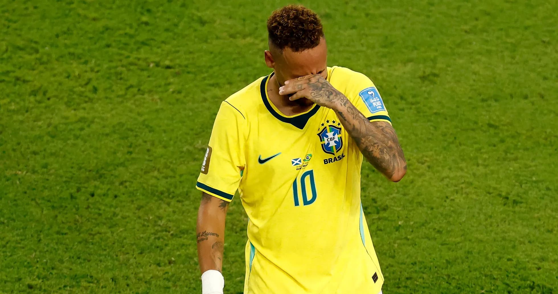 Player in yellow jersey wiping face on field
