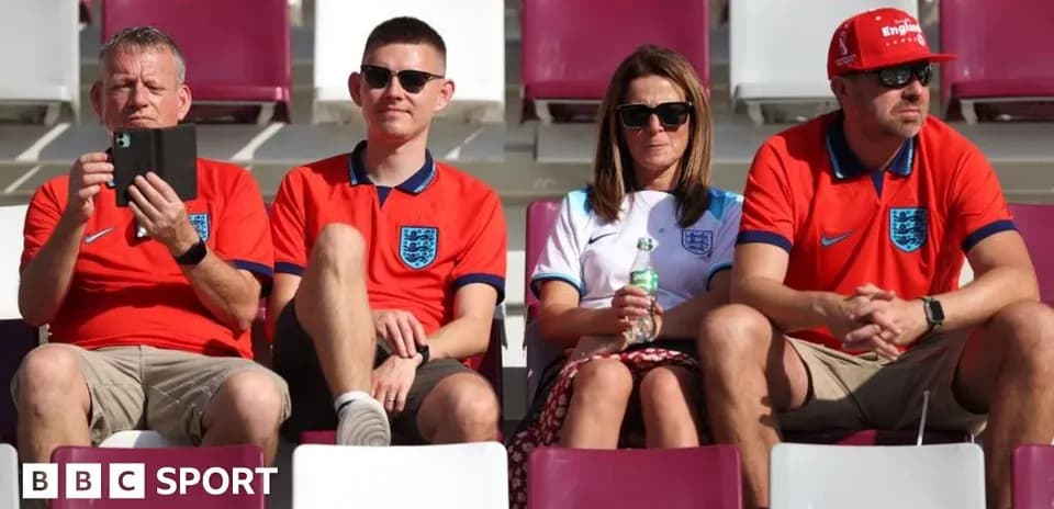 Fans wearing England shirts sitting in stadium seats