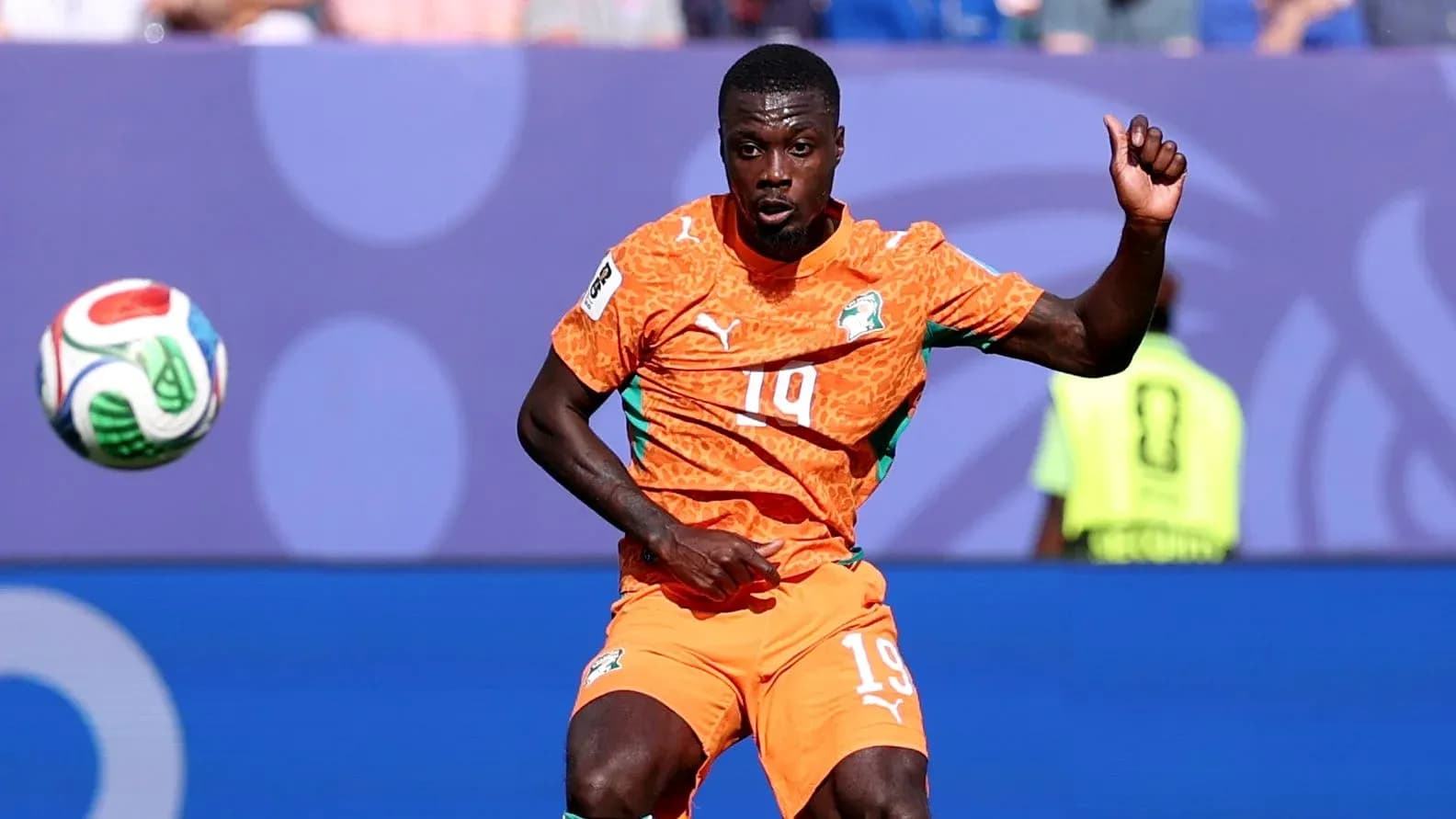 Player in orange kit controlling the soccer ball