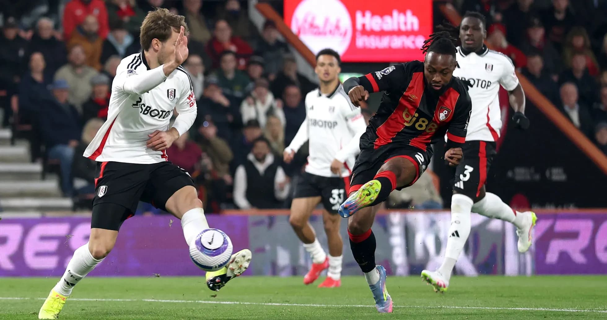 Fulham player challenges Bournemouth player for the ball