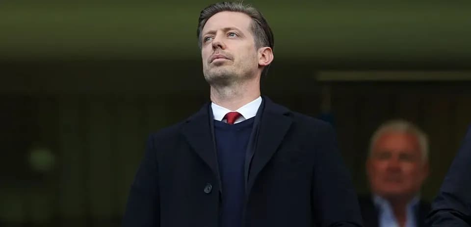 Man in a black coat observing from a stand