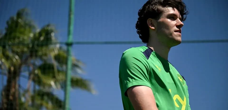 Player standing on training pitch in green kit