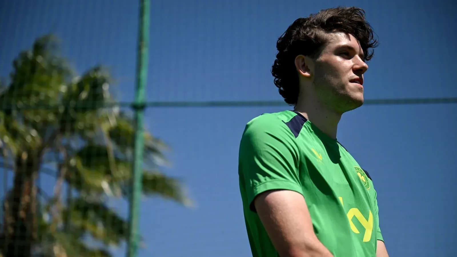 Player standing on training pitch in green kit