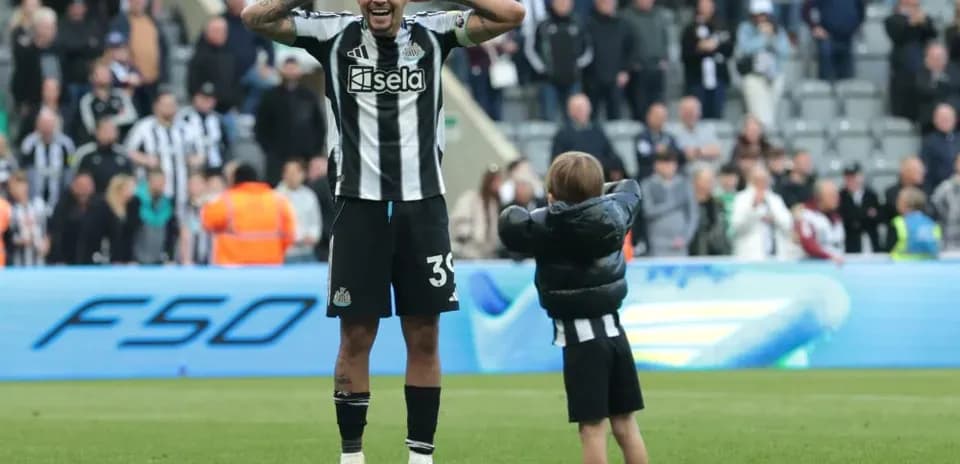 Newcastle player celebrating with a child on pitch
