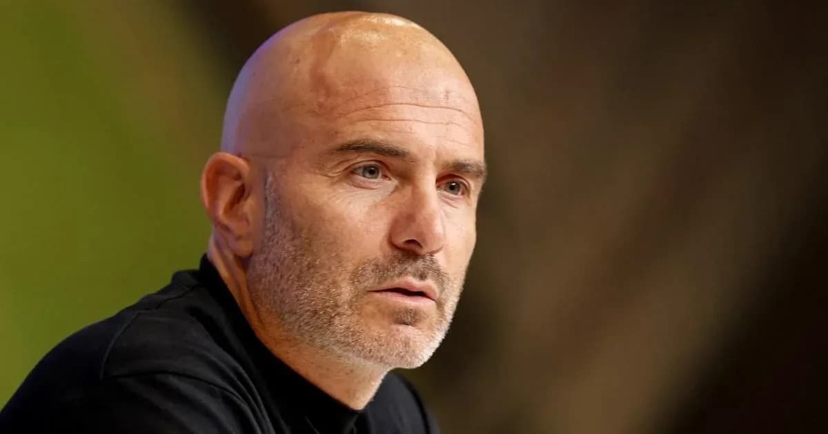 Coach speaking at press conference with serious expression