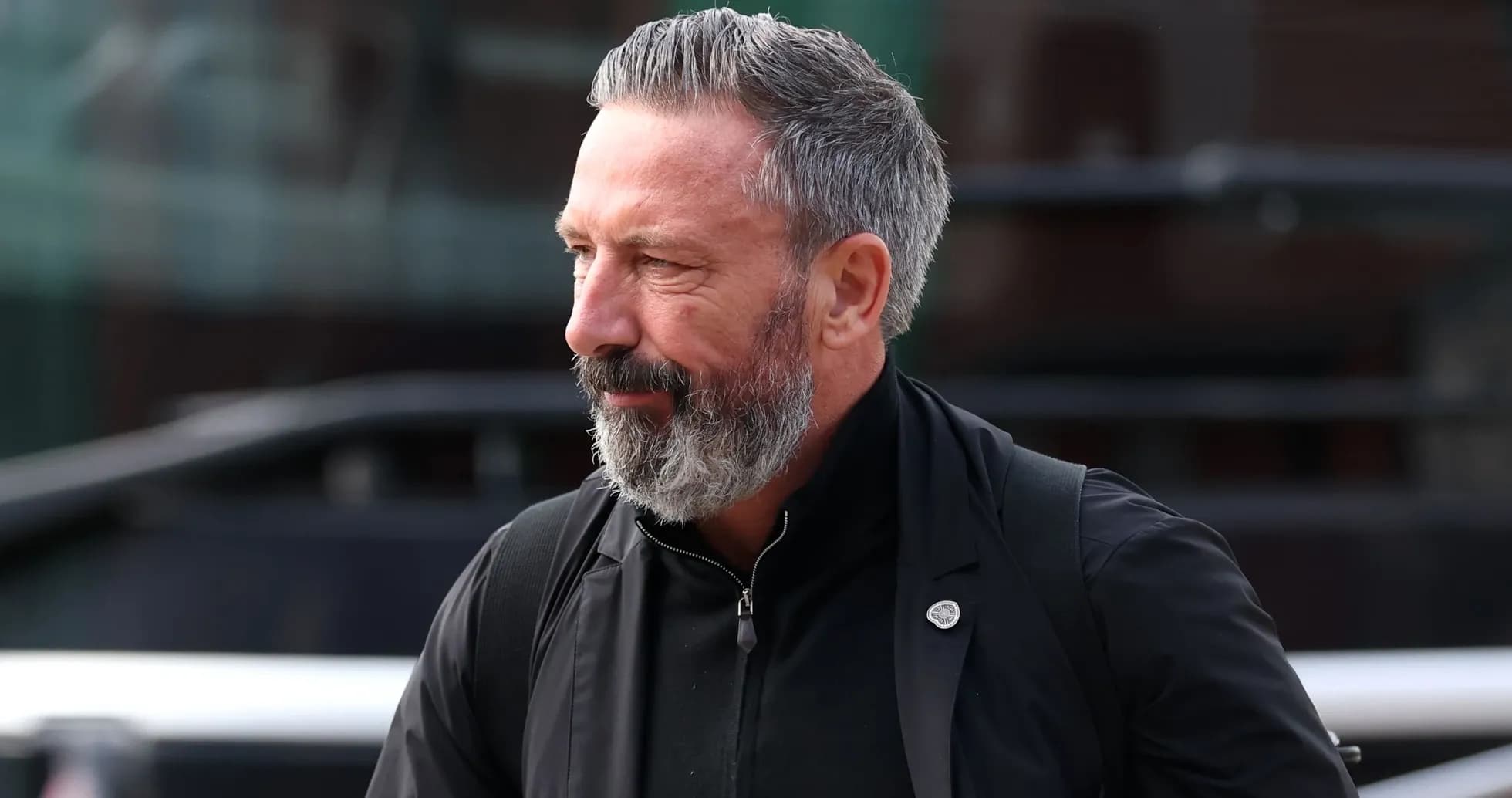 Man with beard walking near team bus
