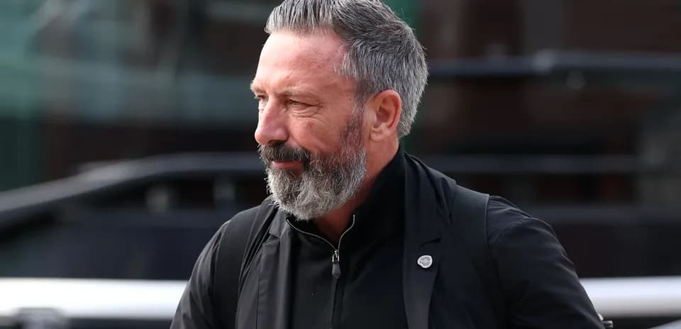 Man with beard walking near team bus