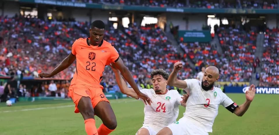 Player in orange jersey evading two defenders on field
