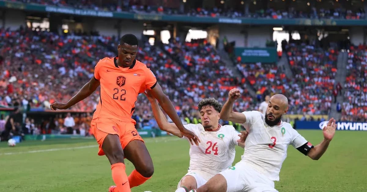 Player in orange jersey evading two defenders on field