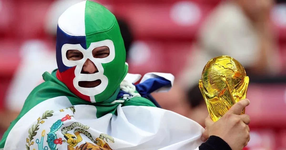 Fan wearing mask holds World Cup trophy