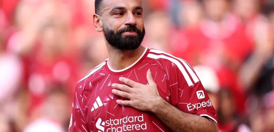 Player in red jersey gesturing to fans