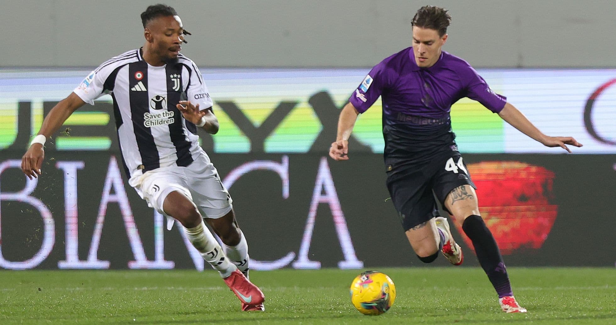 Juventus player challenging Fiorentina player for ball