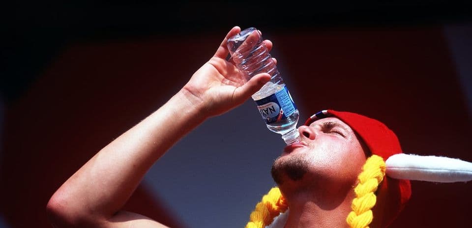 Person in a hat drinking water from bottle