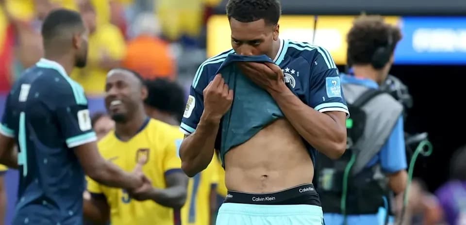 Player removing shirt after match, teammates in background