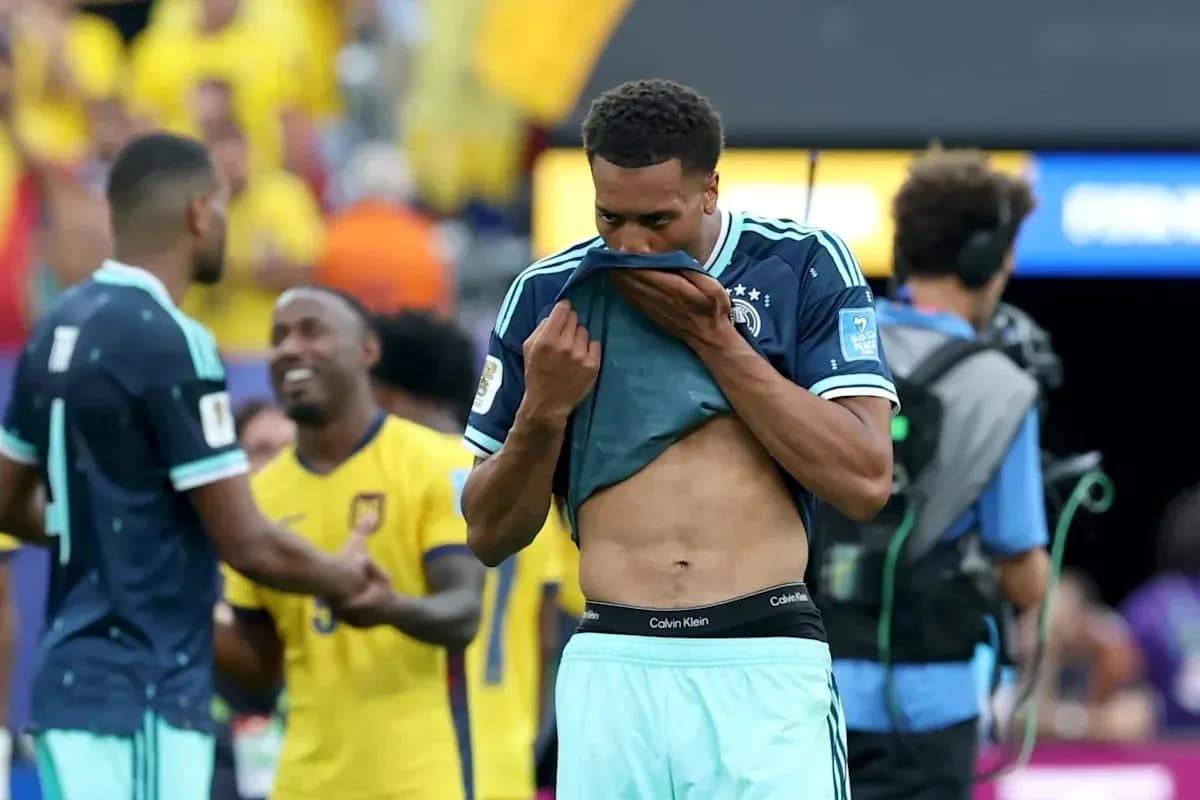 Player removing shirt after match, teammates in background