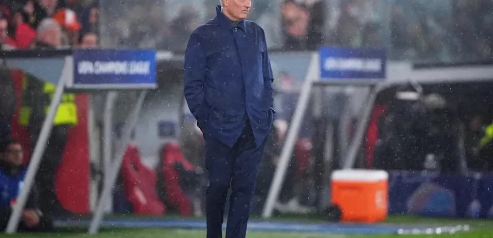 Coach standing on the sidelines during a rainy match