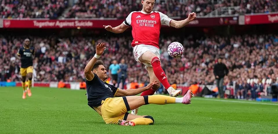 Arsenal player evading tackle during match