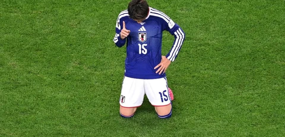 Japanese player kneeling on the pitch during match