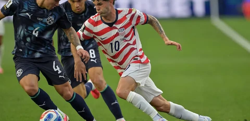 Christian Pulisic dribbling past two defenders during match