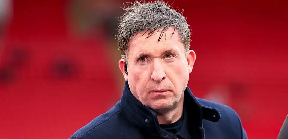 Man in coat with ear piece on stadium backdrop