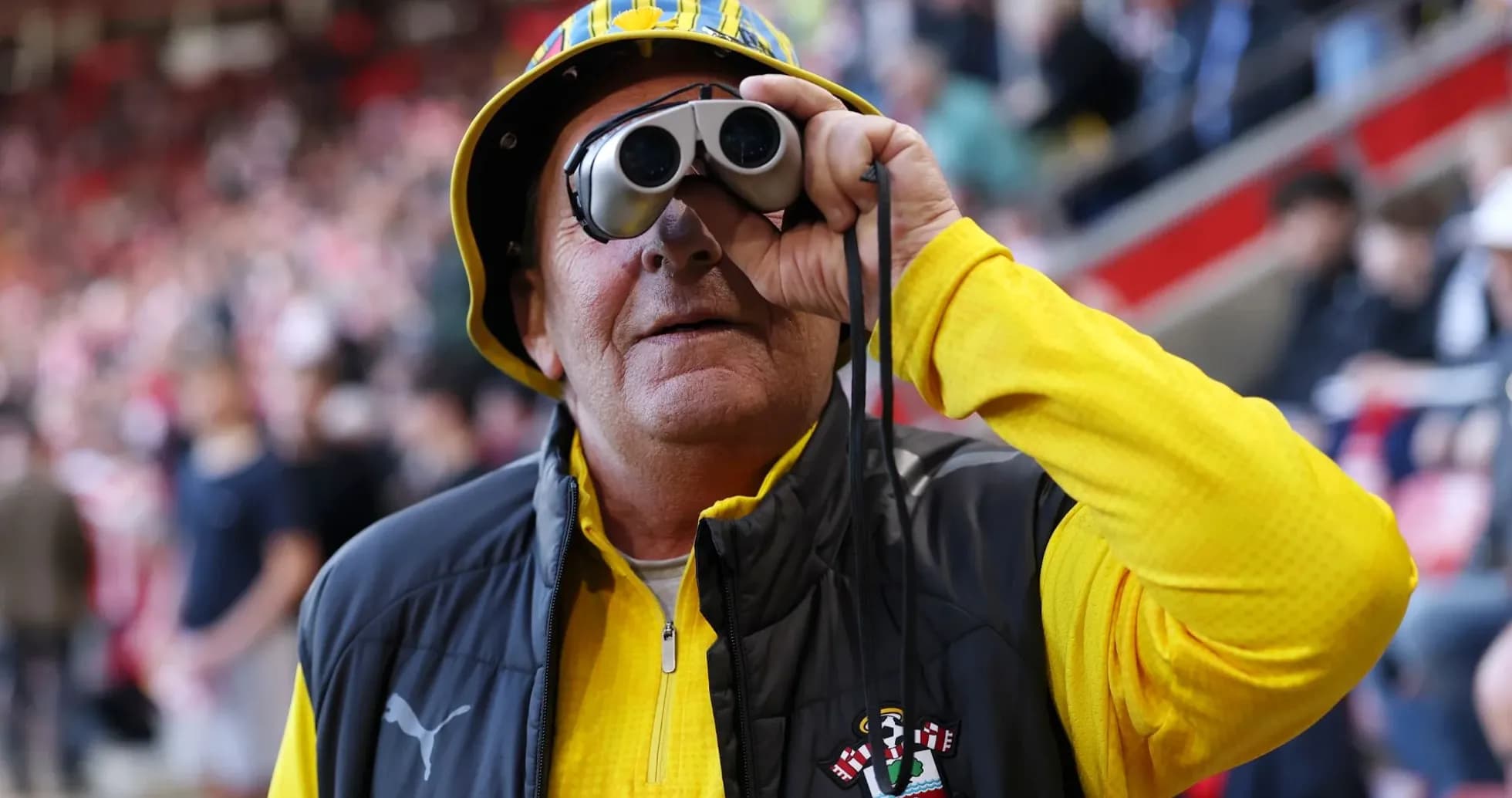 Fan wearing binoculars at a football match