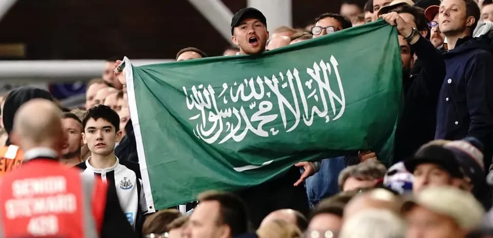Fans holding Saudi Arabian flag in stadium