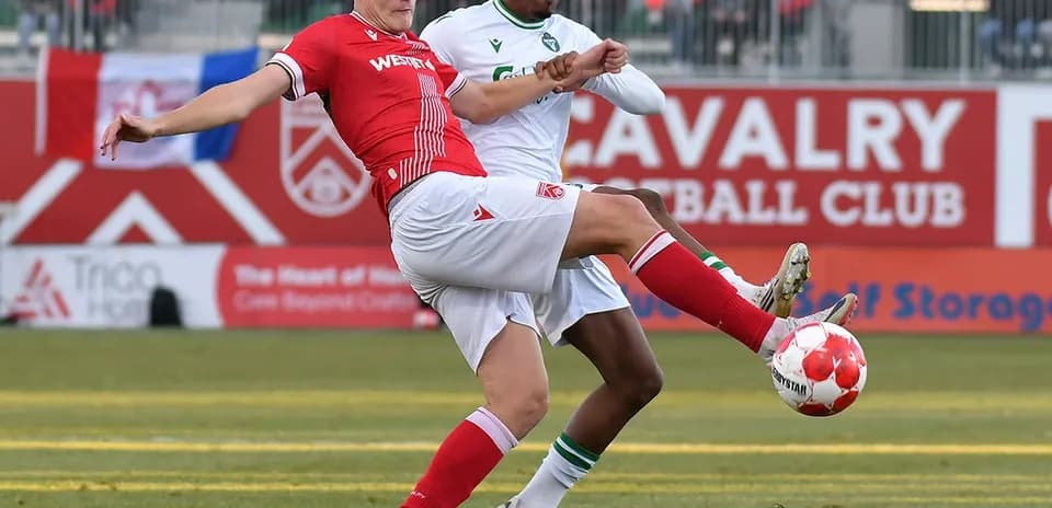 York United player tackling Cavalry FC opponent