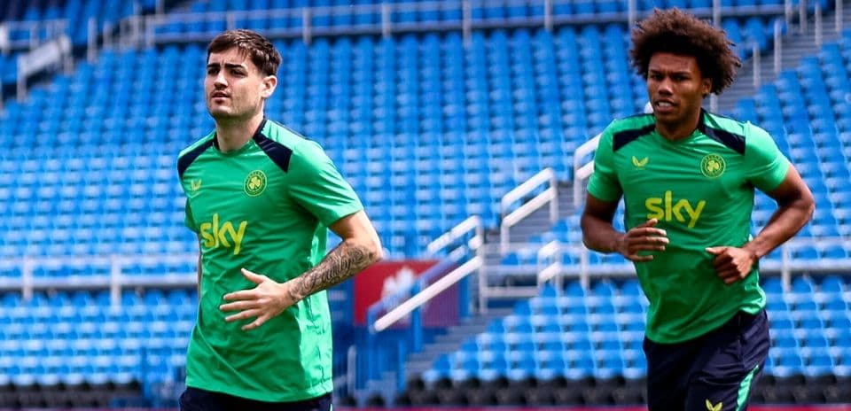 Two players jogging on training pitch before session