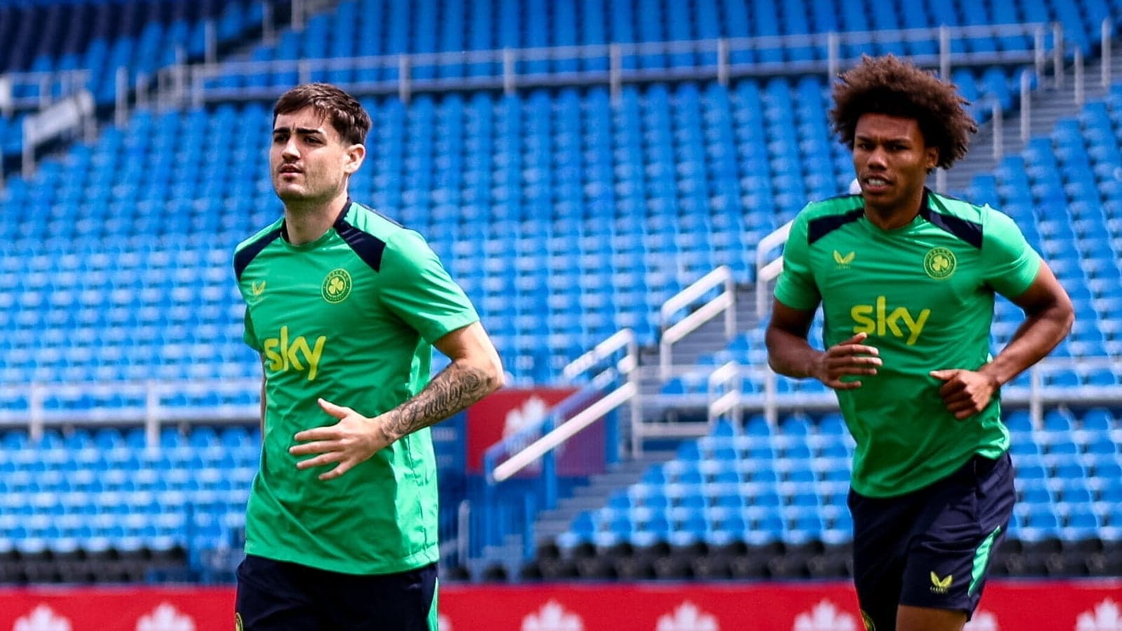 Two players jogging on training pitch before session