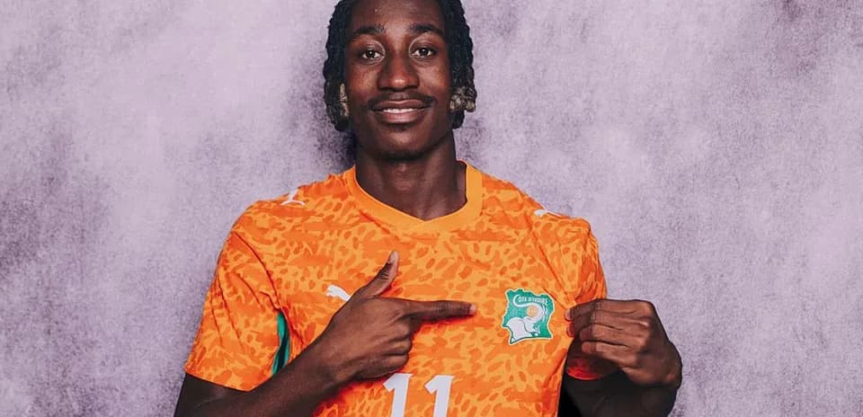 Player in orange jersey pointing to national emblem