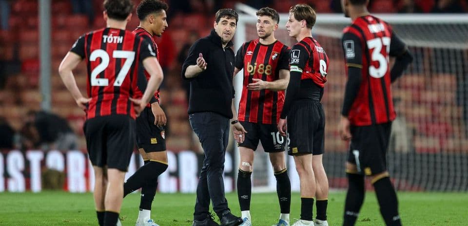 Coach discussing strategy with Bournemouth players on field