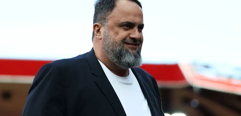Man in a black blazer walking at stadium
