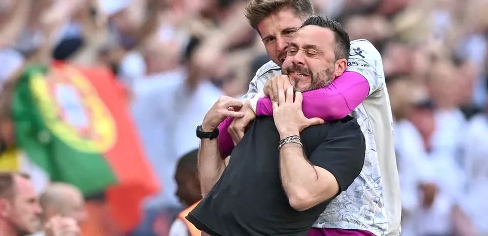 Two coaches celebrating together on the sidelines