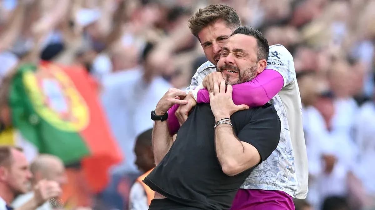 Two coaches celebrating together on the sidelines