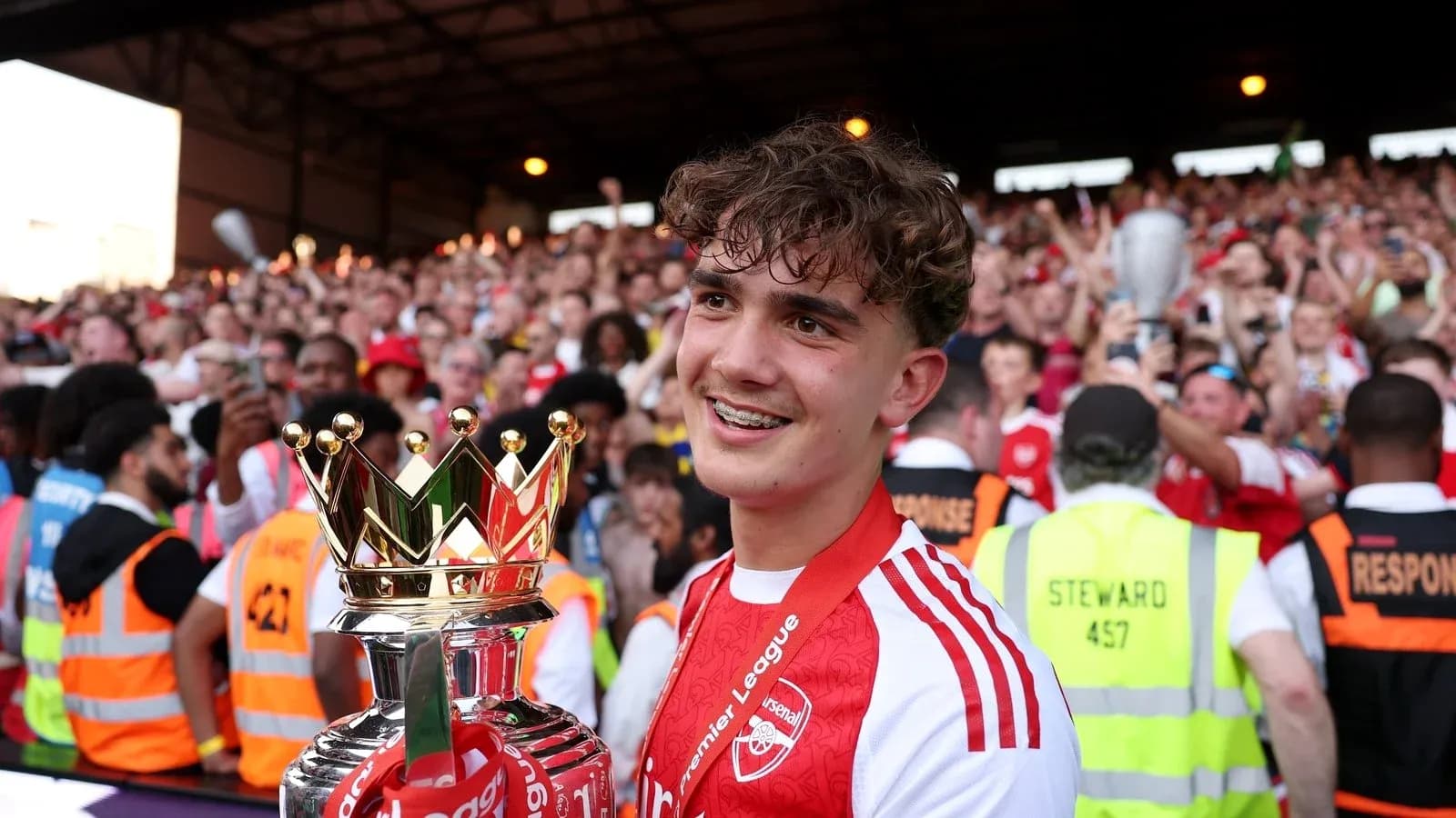 Player holding Premier League trophy in crowd Player holding Premier League trophy in crowd